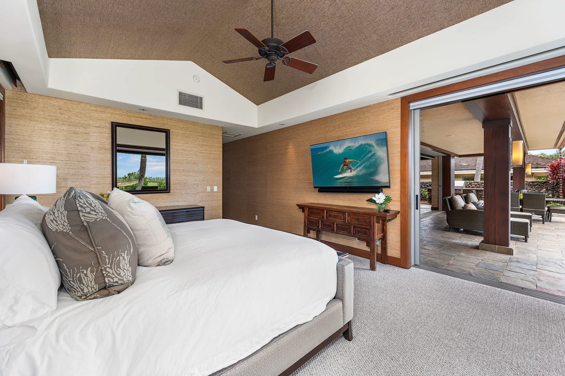 A bedroom with a bed and sliding glass doors opening onto a patio.