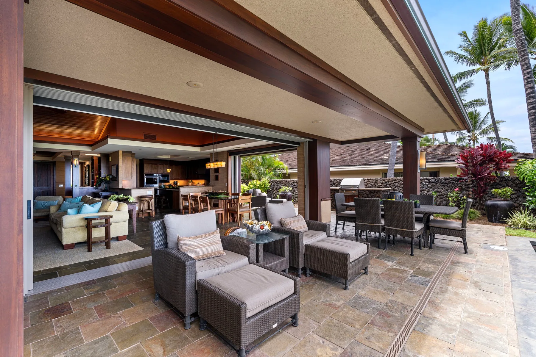 An open-air patio with cushioned seating and a dining table beside the living area.