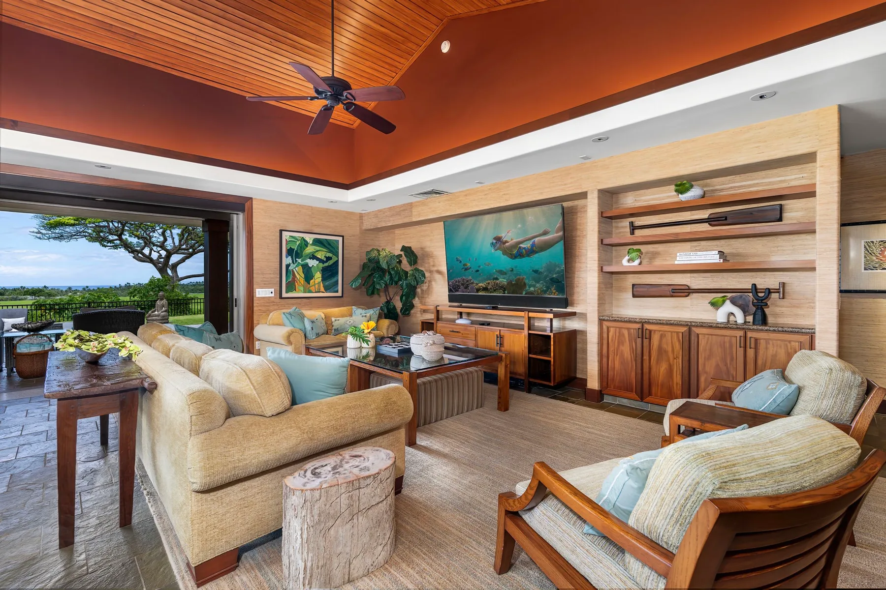A living room with cushioned seating, a television, and open shelves.