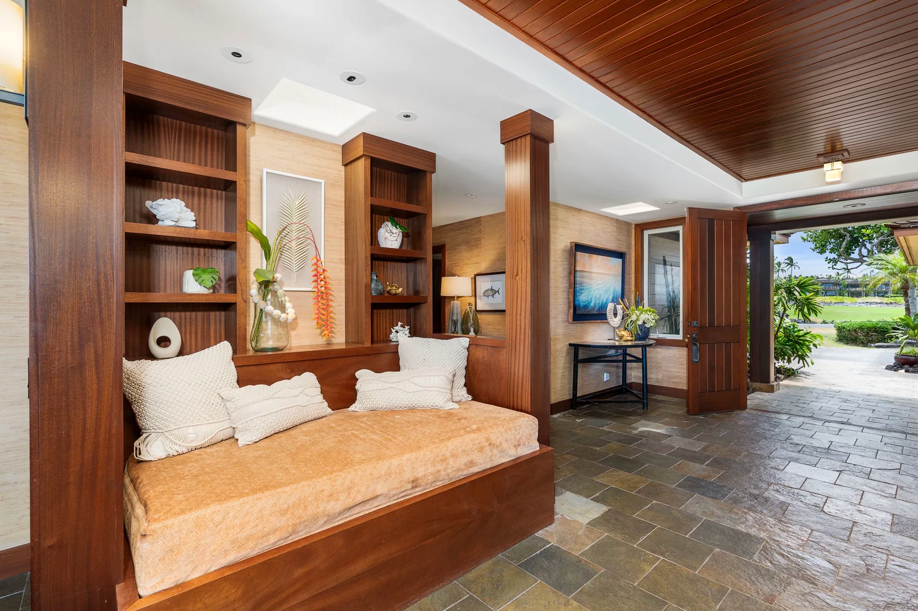 A wood-paneled lounge with built-in seating and an open doorway to greenery.