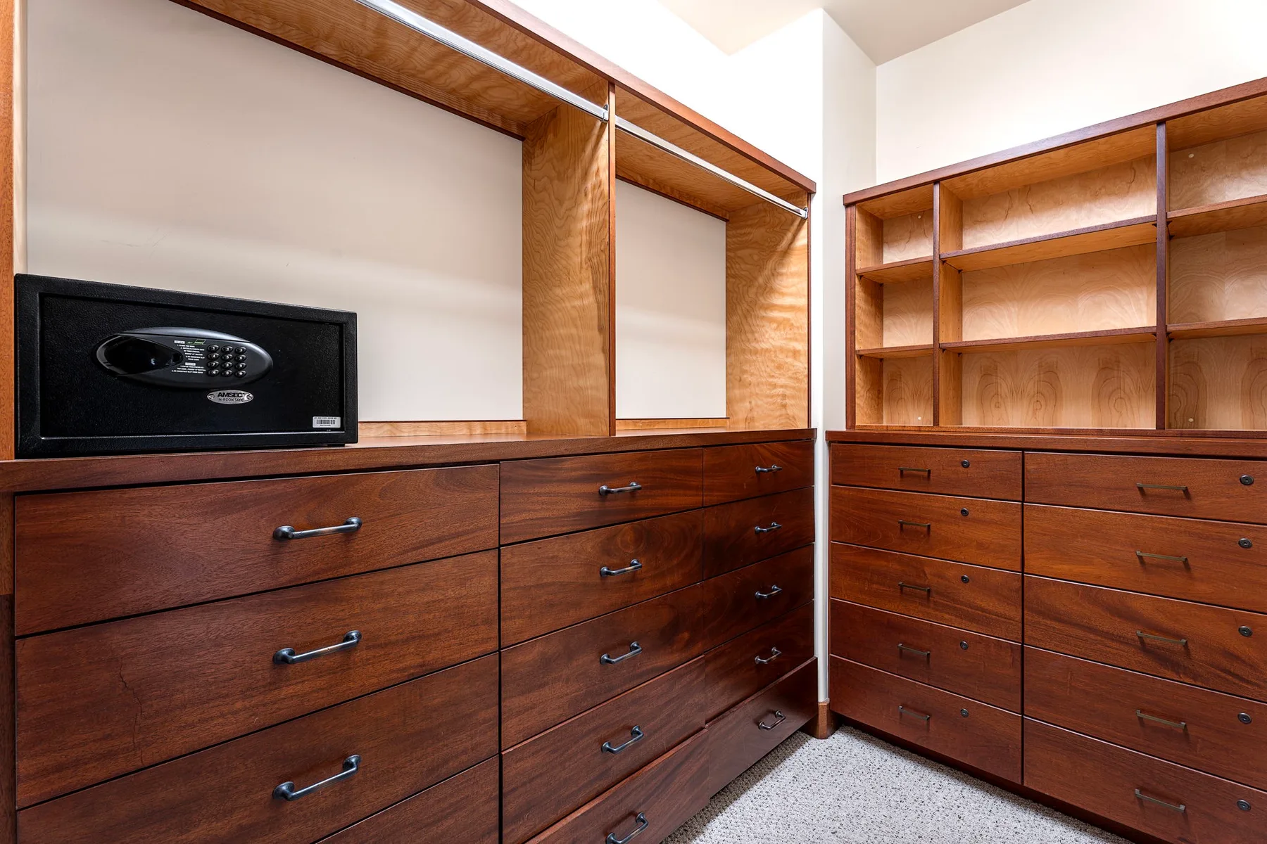 A walk-in closet with wooden drawers, open shelving, and a safe.