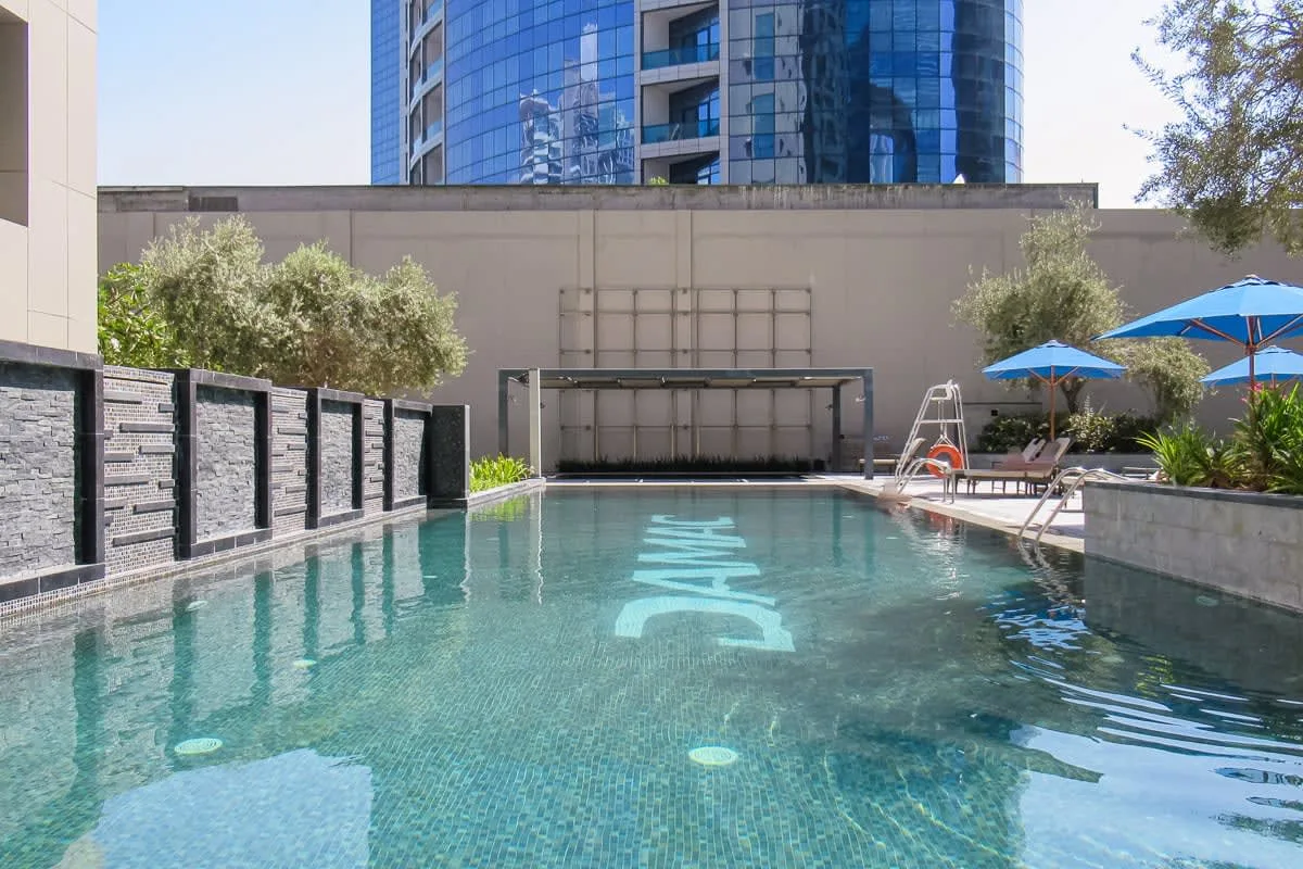 Una piscina al aire libre con asientos y sombrillas azules.