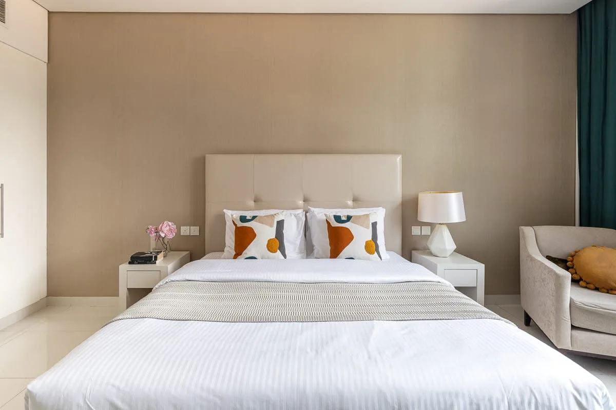 Un dormitorio con una cama bien tendida y una lámpara de noche.