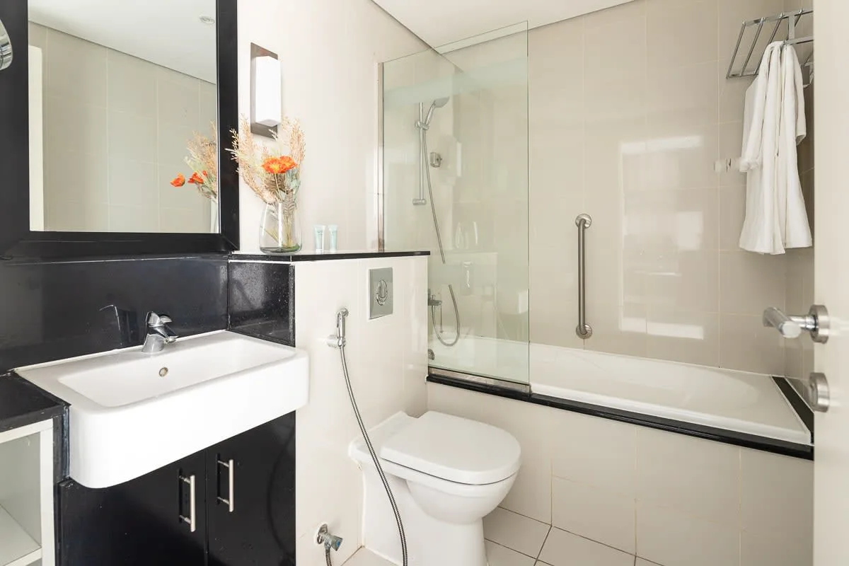 Un baño luminoso con lavabo, inodoro y ducha con mampara de vidrio.