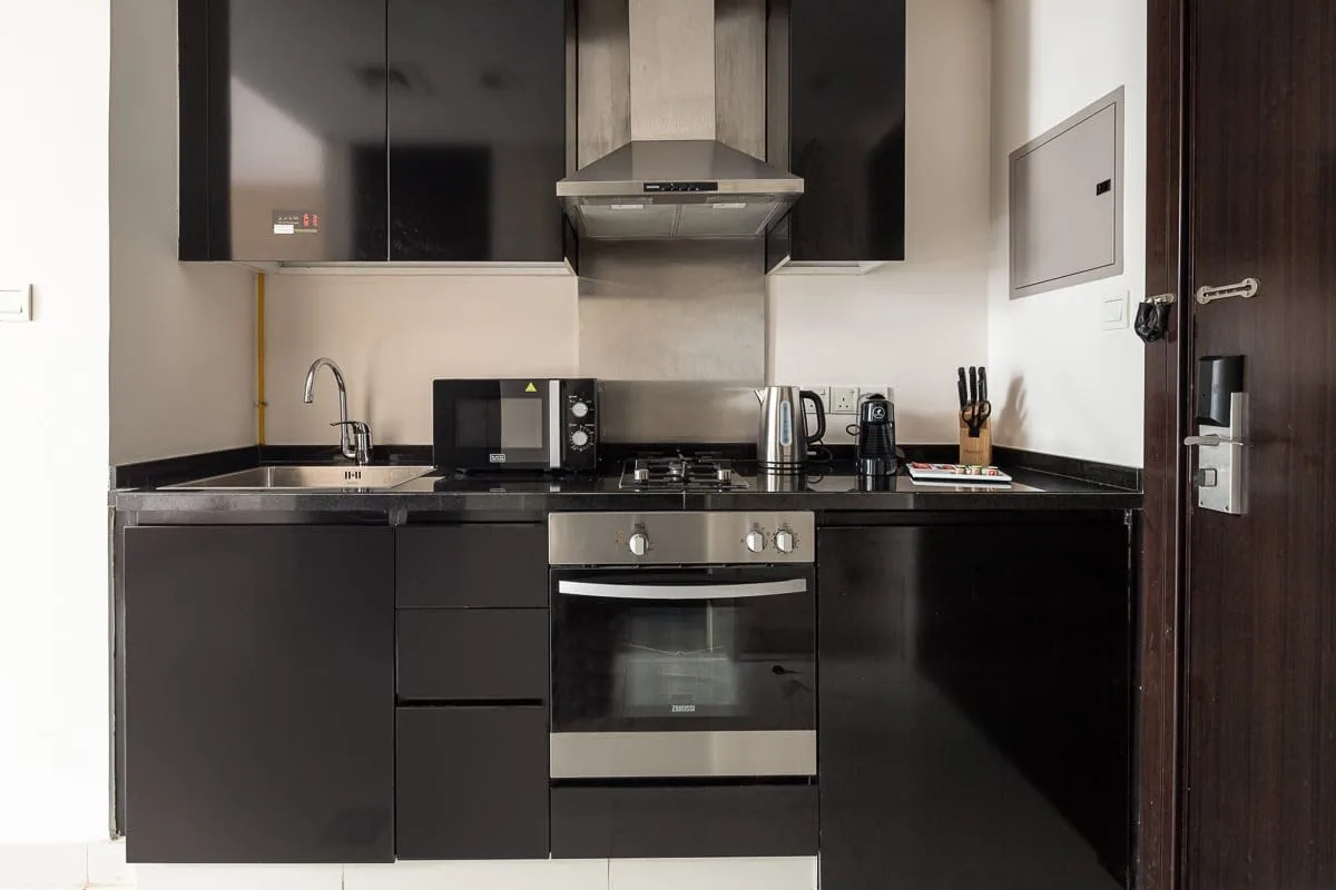 Una cocina compacta con gabinetes oscuros, una placa de cocción y un horno.