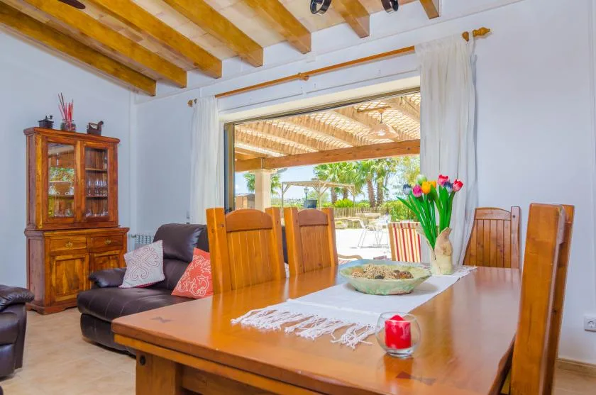 A dining area with a wooden table and chairs beside an open patio doorway.
