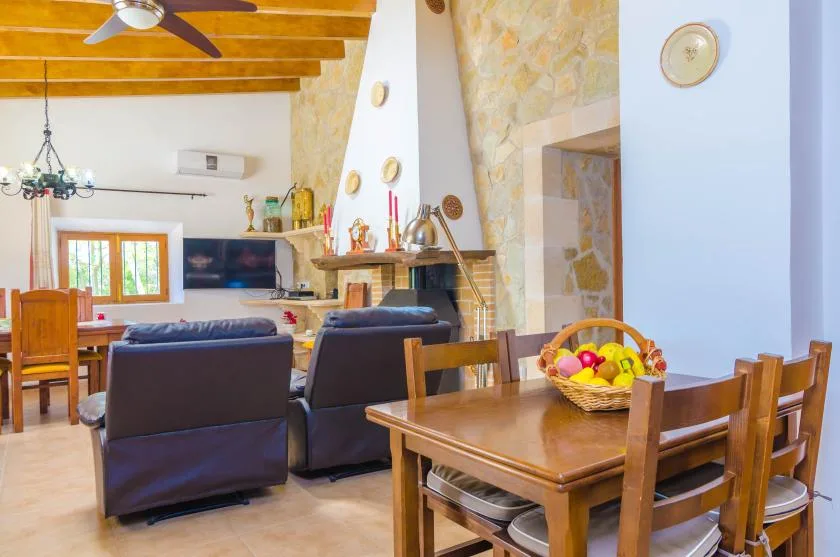 A living and dining room with a television, fireplace, and wooden dining table.