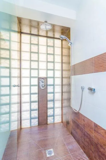 A tiled shower area with a wall-mounted showerhead and floor drain.