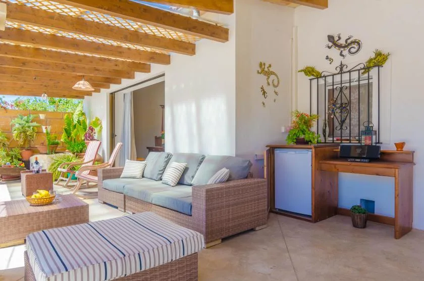 A covered patio seating area features a wicker sofa and a wooden bar counter.