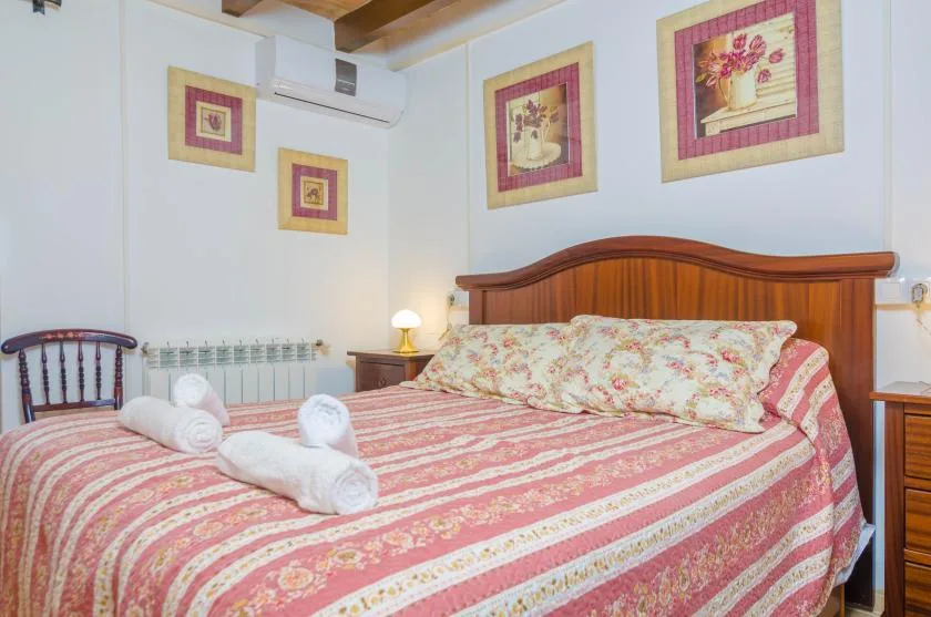 A bedroom with a wooden bed, floral bedding, and framed floral pictures.