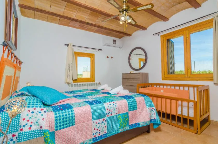 A bedroom with a colorful patchwork bedspread and wooden crib.