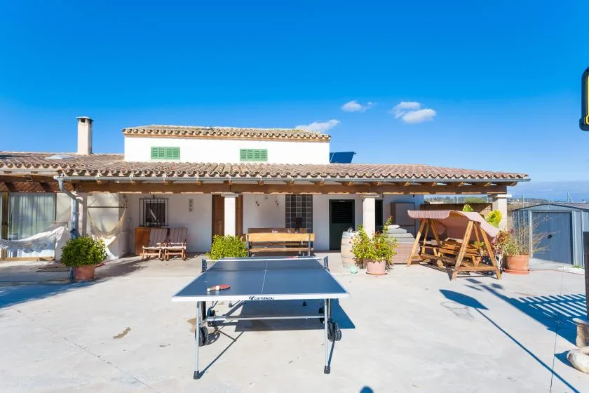 A patio with a table tennis table and a covered seating area.