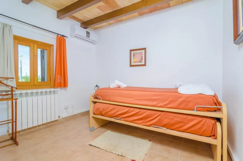 A bedroom with an orange bed beside a window and radiator.
