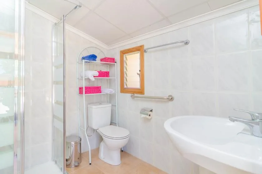 A bright bathroom with a toilet, sink, and glass shower enclosure.
