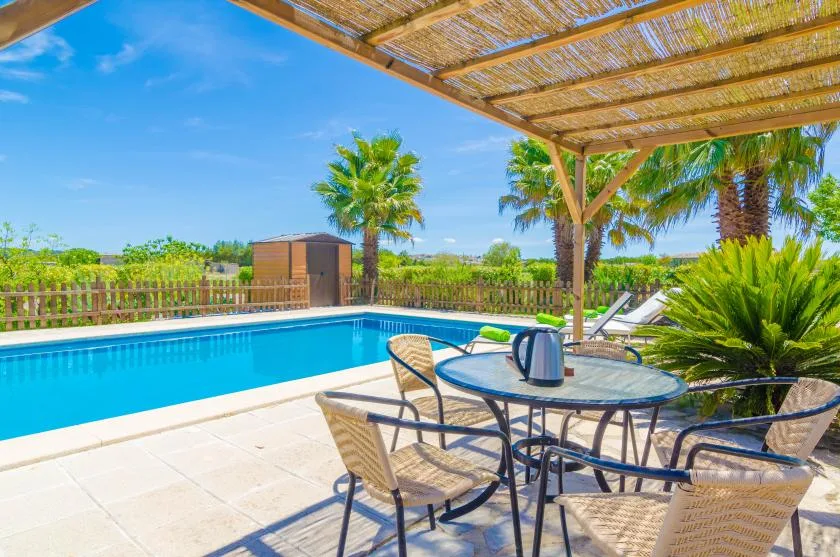 A swimming pool beside a shaded patio with outdoor seating.