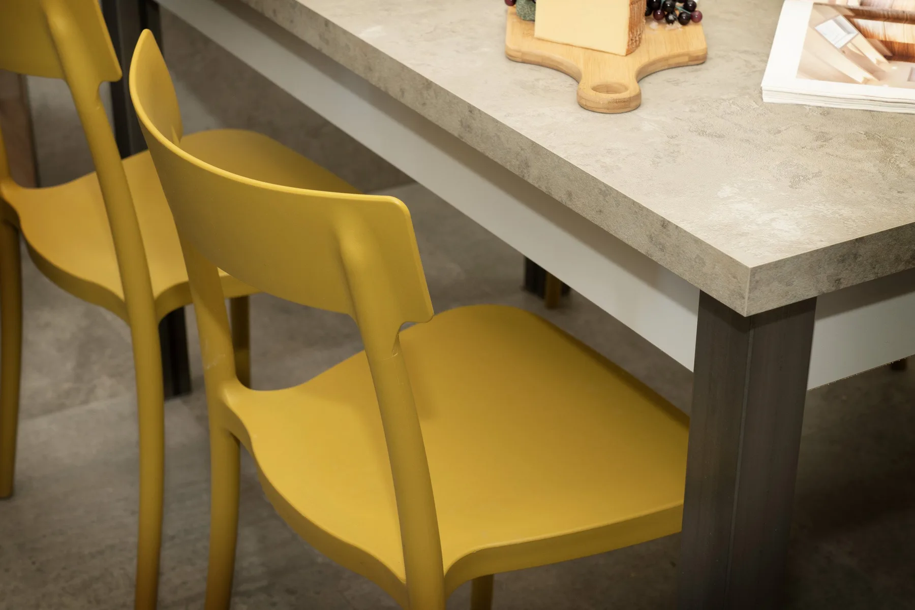 Comedor con asientos amarillos alrededor de una mesa de piedra clara.