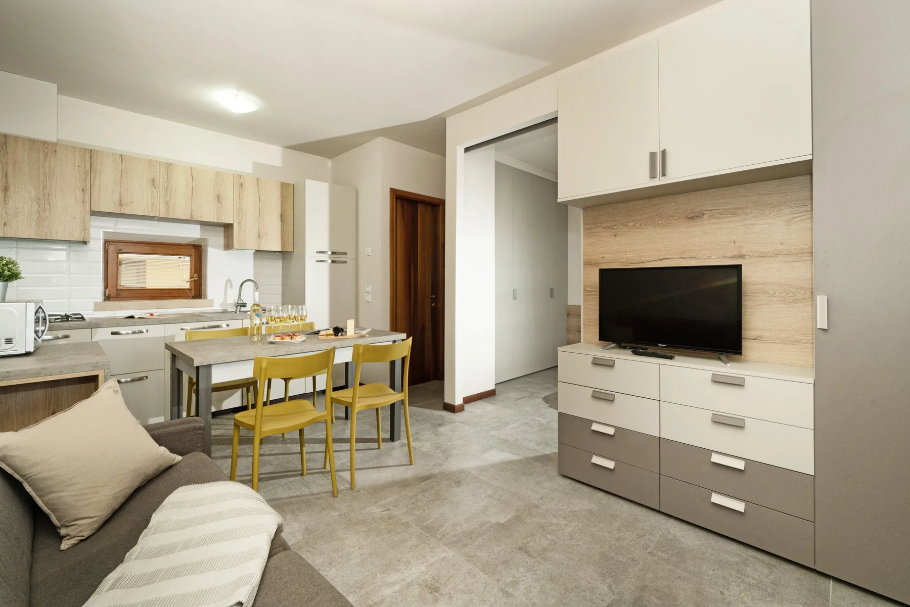 A modern living and dining area with a television, table, and chairs.