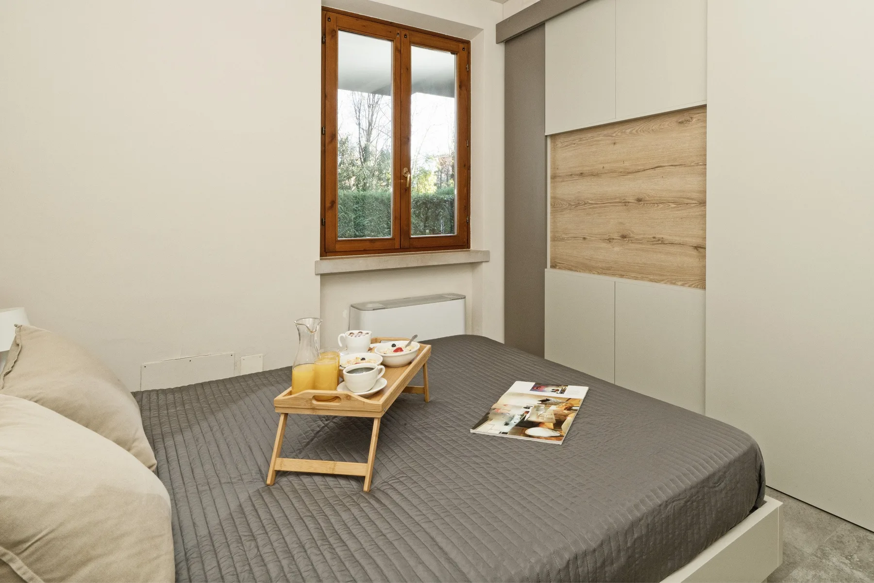 A bedroom with a bed, a small tray of refreshments, and a window.