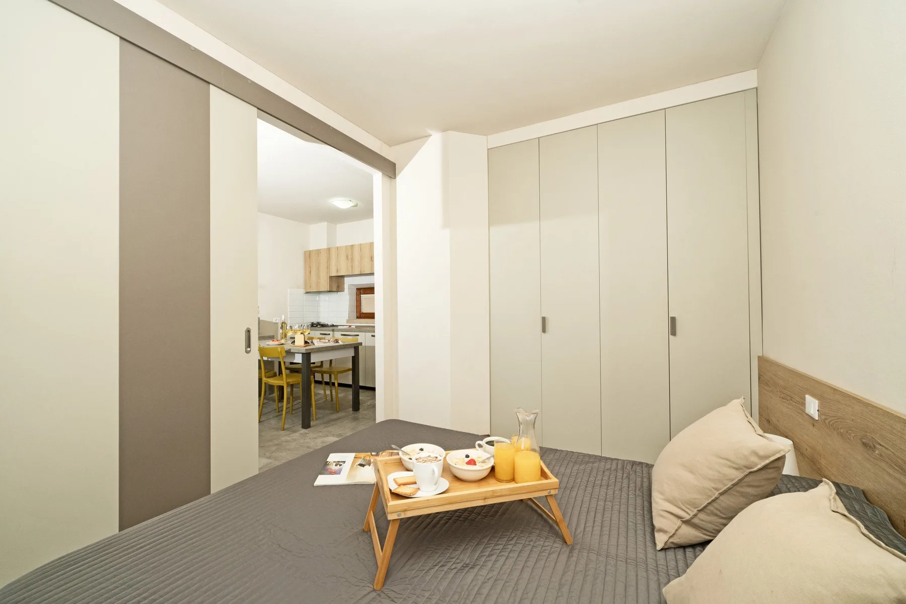 A bedroom with a low bed, bedside table, and closed built-in cabinets.