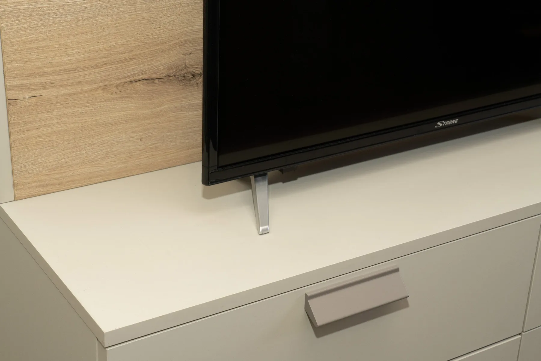 A television sits on a white cabinet against a wood-paneled wall.