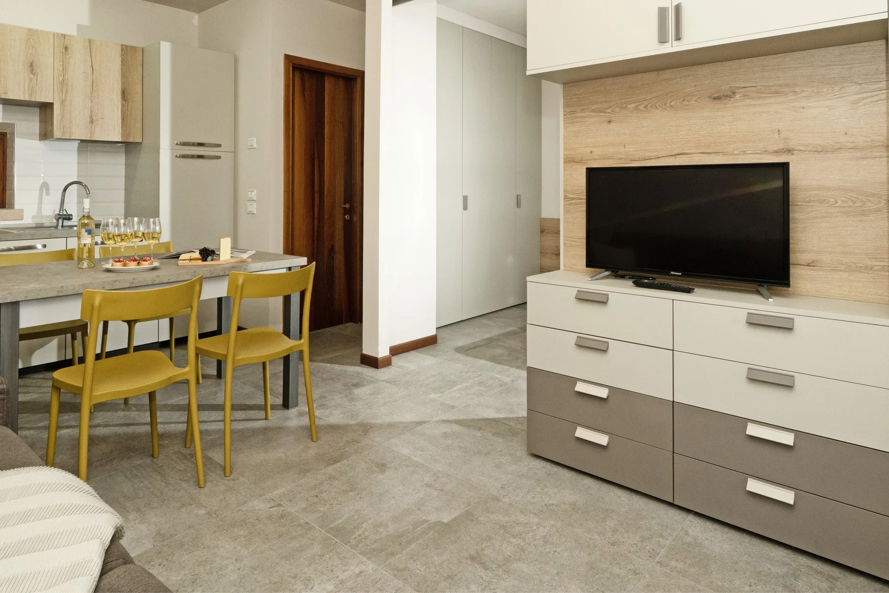 A modern kitchen and dining area with a television on a built-in cabinet.