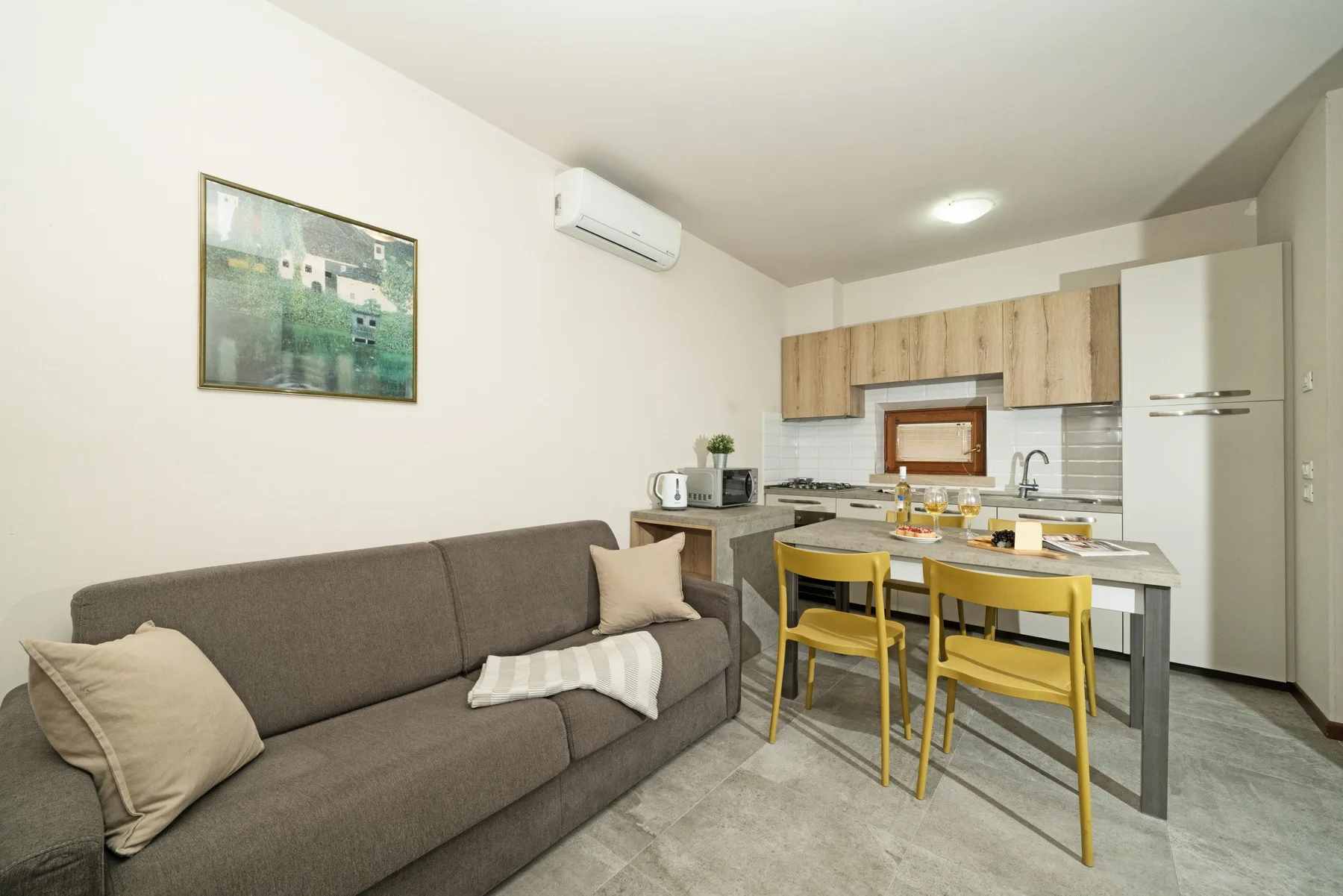A living and dining area with seating, a table, and a compact kitchen.