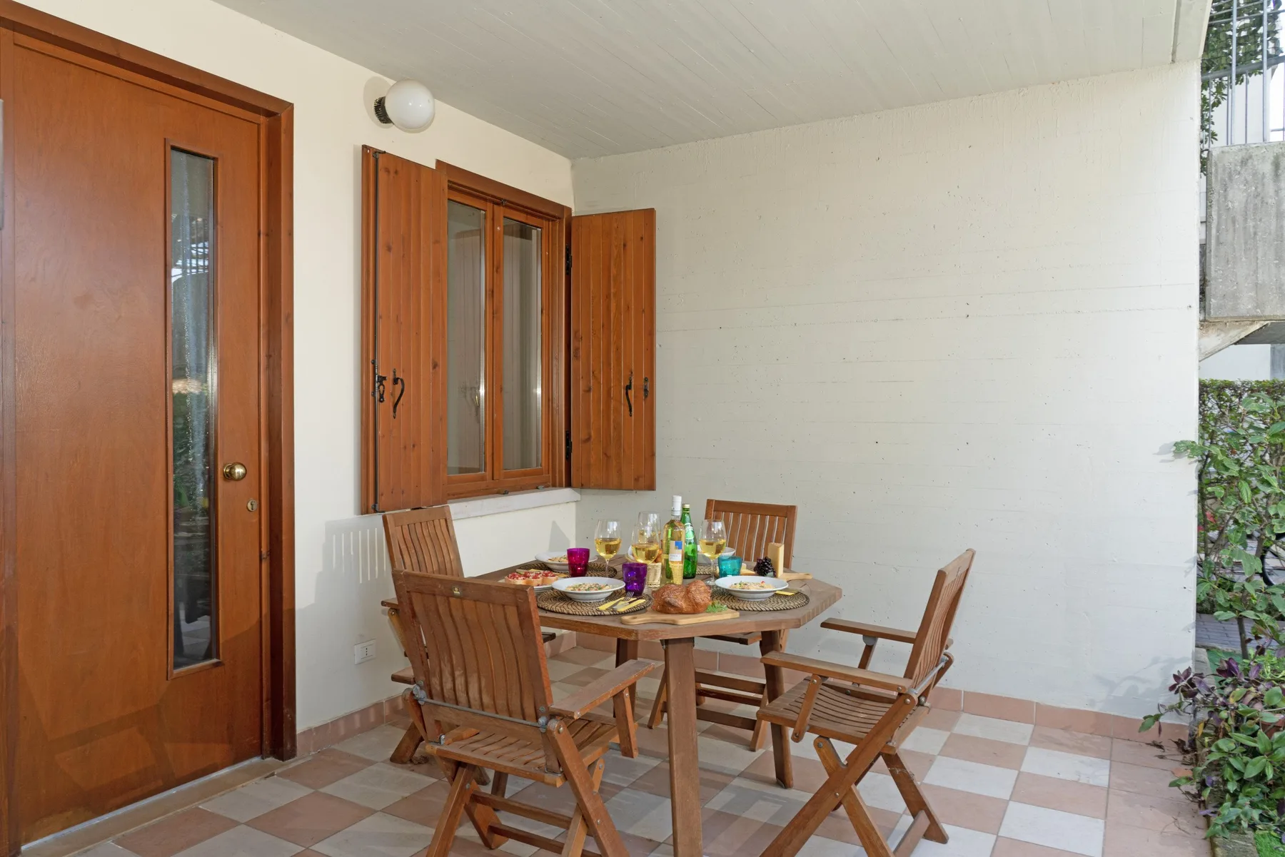 A covered patio dining area with a wooden table and seating.