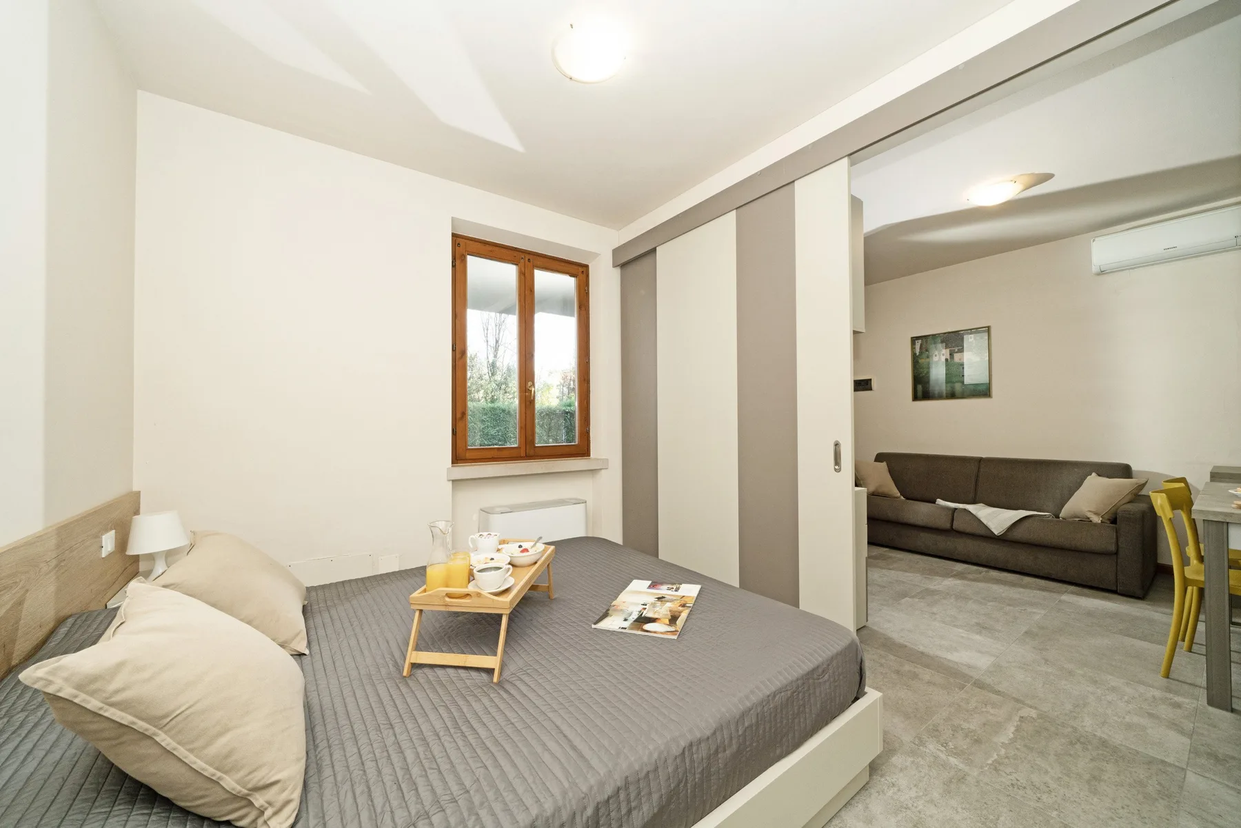 A bedroom with a bed, a small table, and a window.