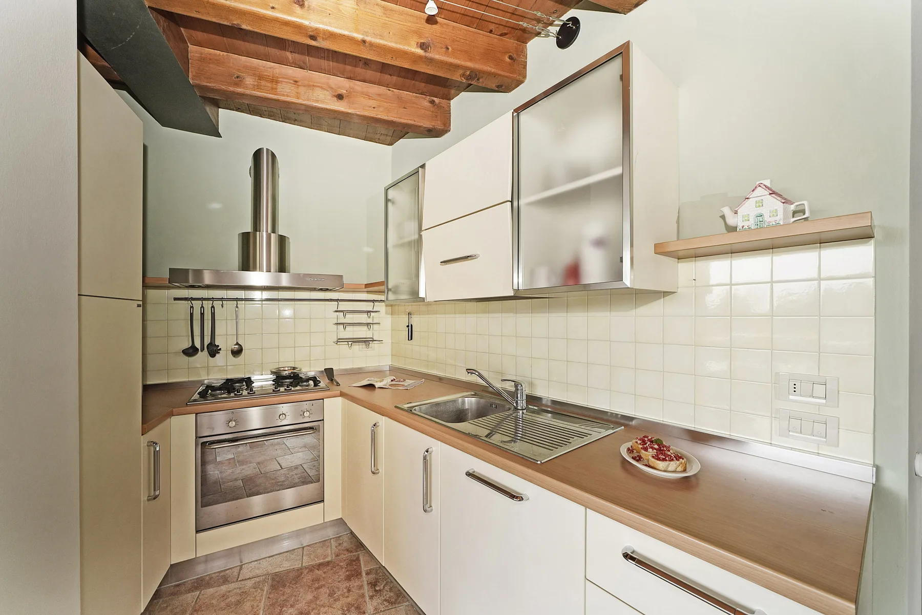 Una cocina con gabinetes blancos, una estufa y un fregadero junto a la encimera.
