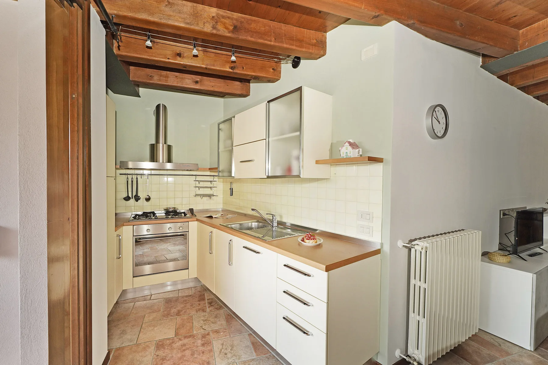 Una cocina con vigas de madera en el techo y armarios claros.
