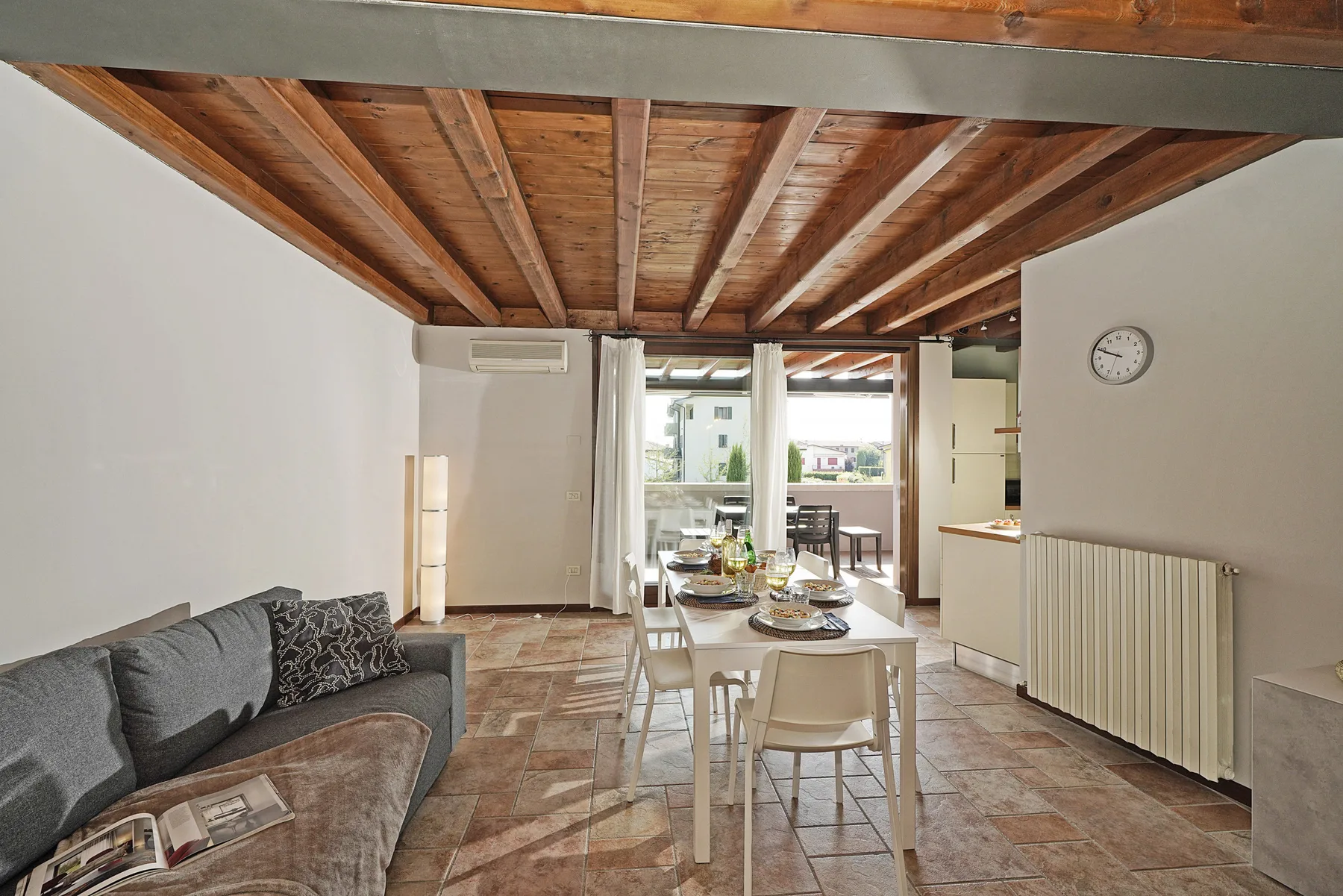 Una sala de estar y comedor con una mesa junto a un sofá gris.