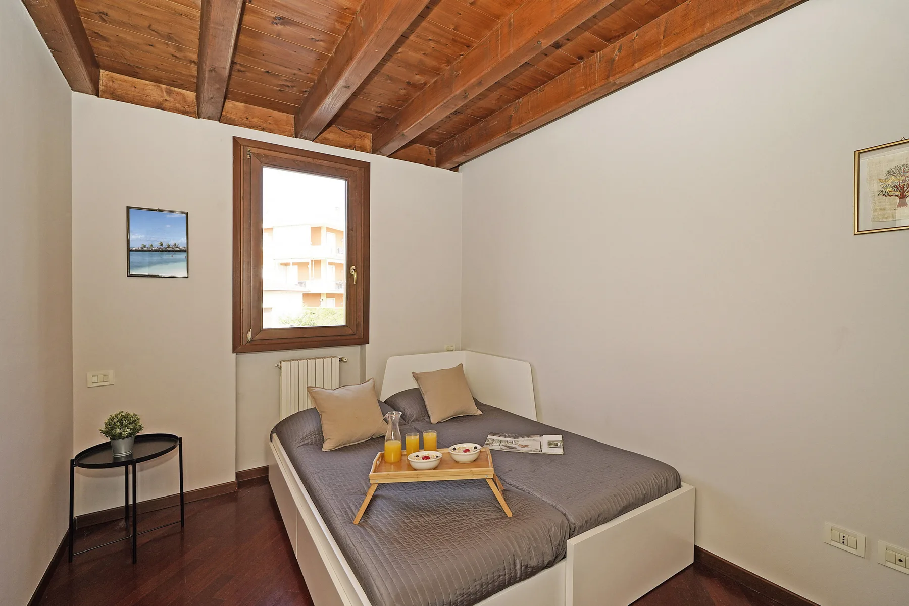 Un dormitorio con una cama bajo un techo de madera y una ventana.