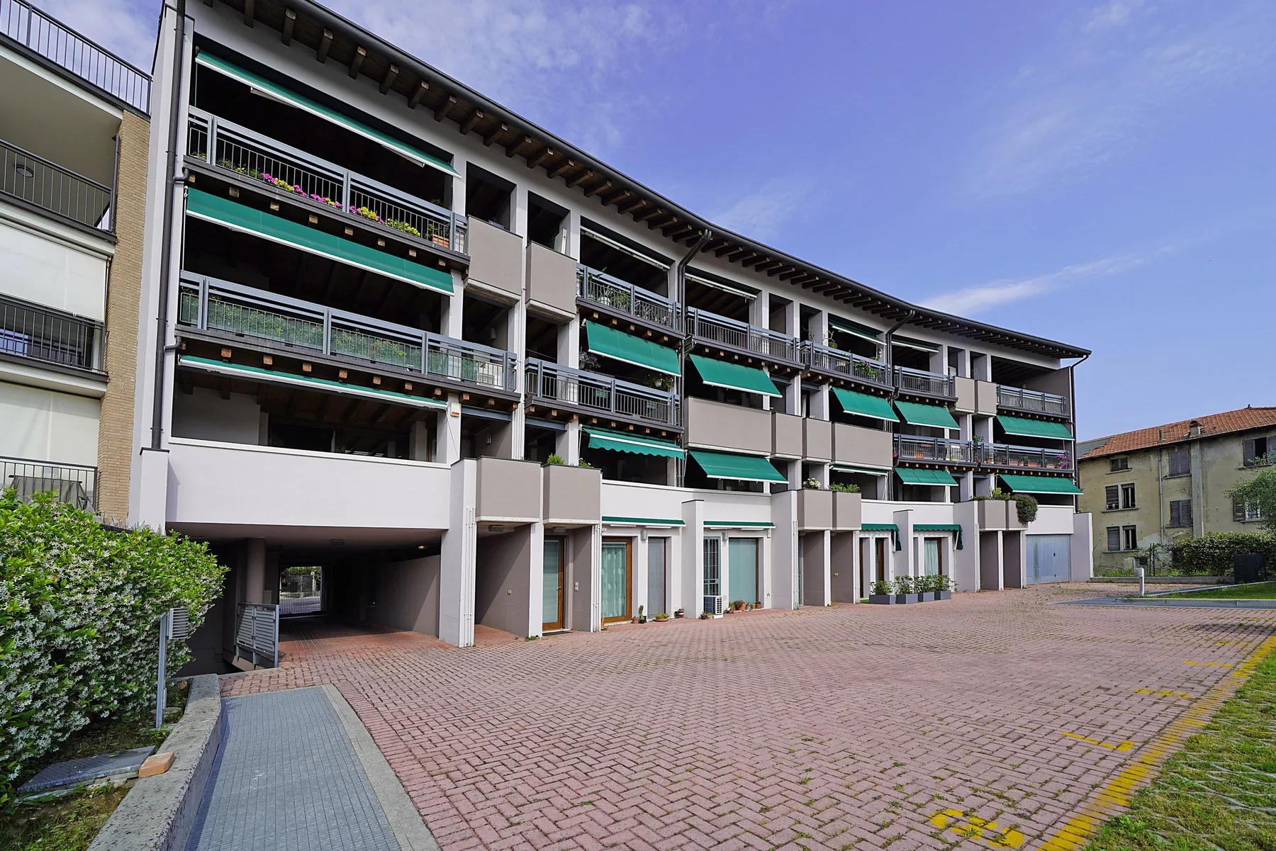 Un edificio de apartamentos de varias plantas da a un amplio patio pavimentado.