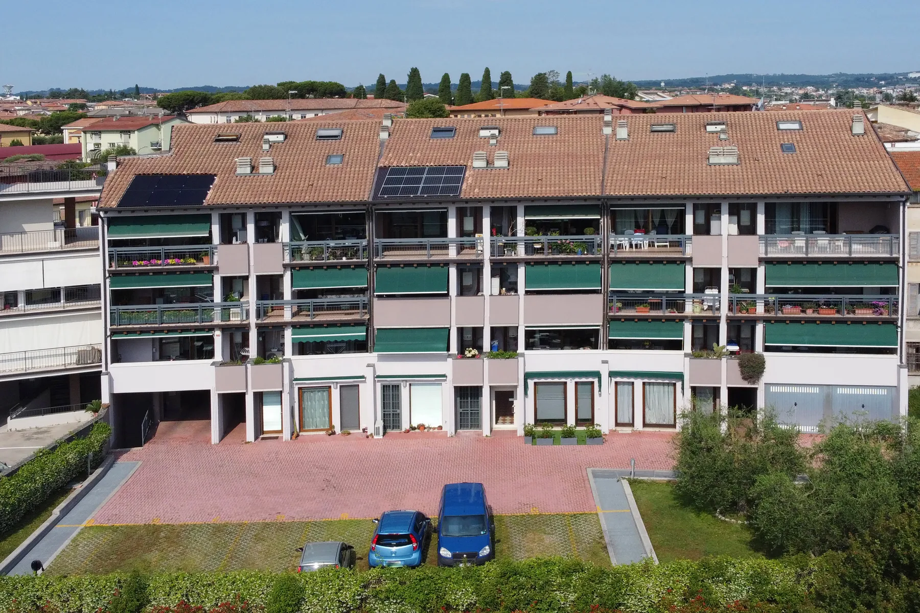 Un edificio de apartamentos de varias plantas con balcones, ventanas en el tejado y paneles solares.