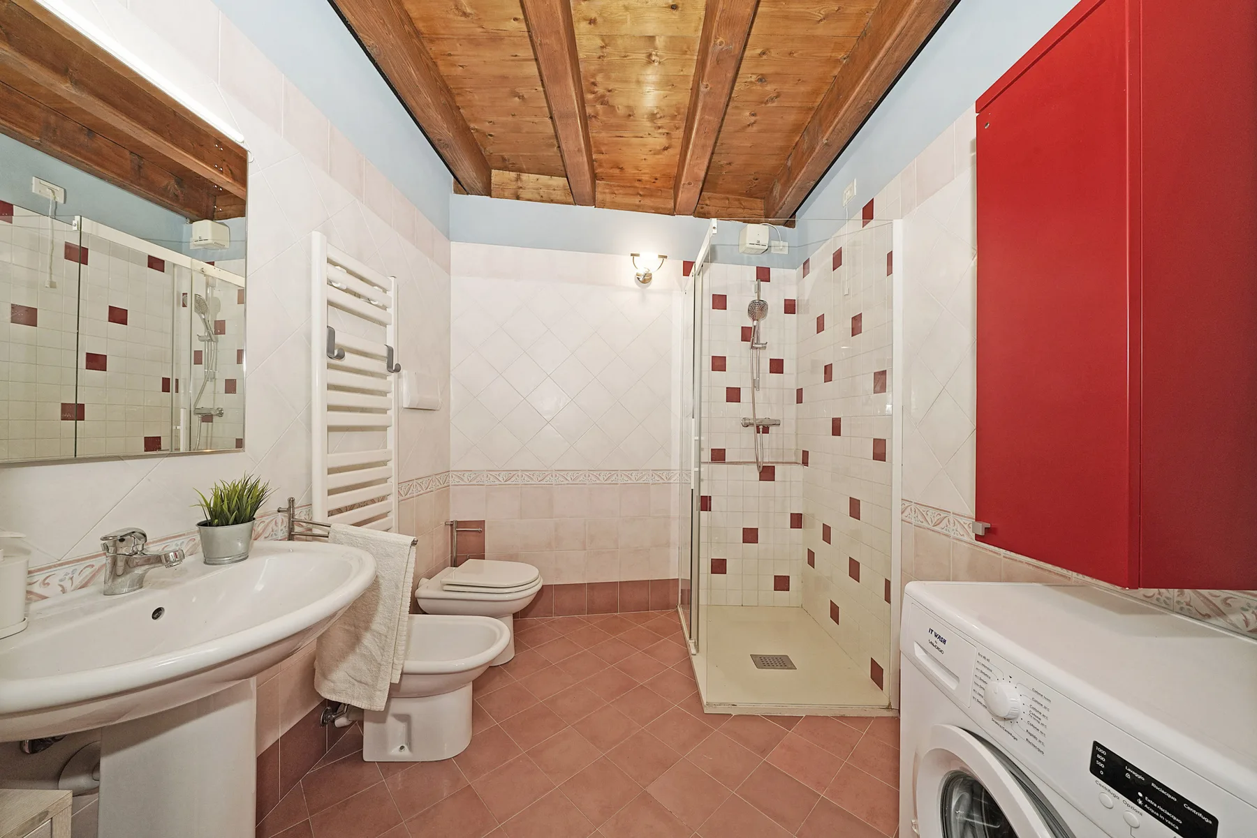 Un baño alicatado con lavabo, inodoro, ducha y lavadora.