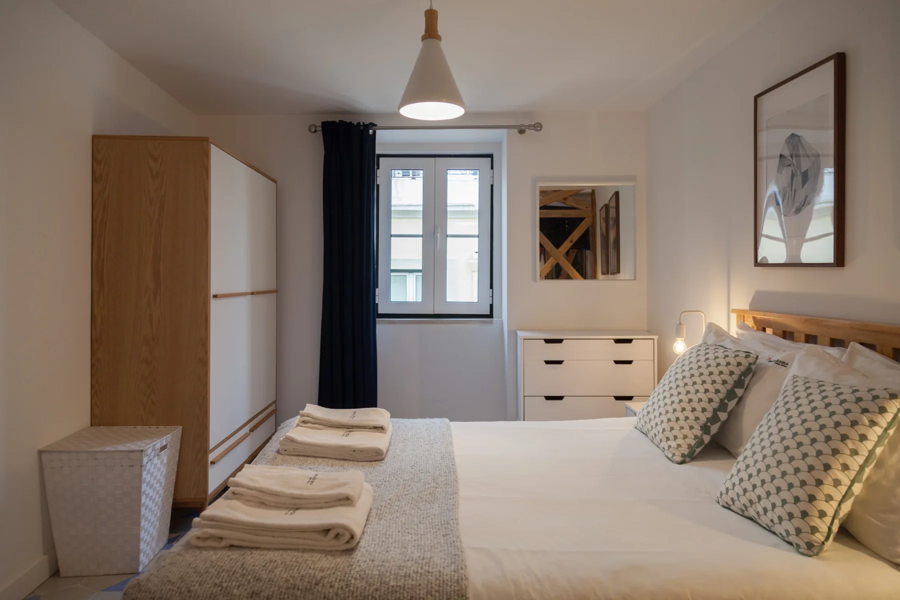 Un dormitorio con una cama bien hecha, toallas dobladas y una ventana.