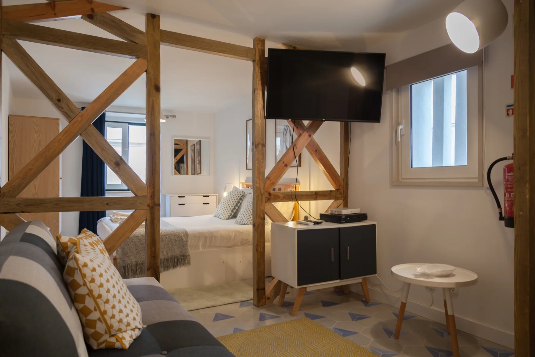 Un estudio con una cama, asientos y un televisor sobre un mueble.