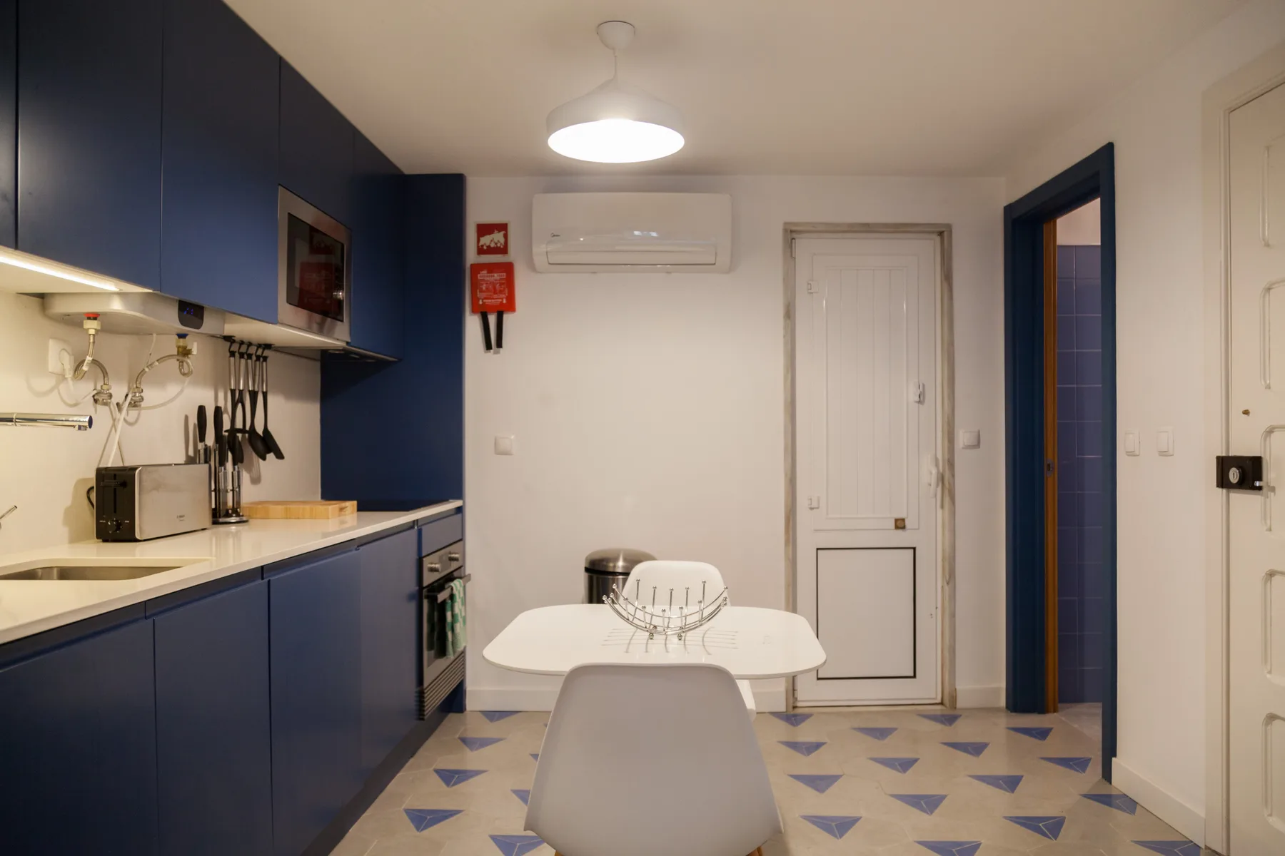 Una cocina compacta con zona de comedor, armarios azul oscuro y una mesa.