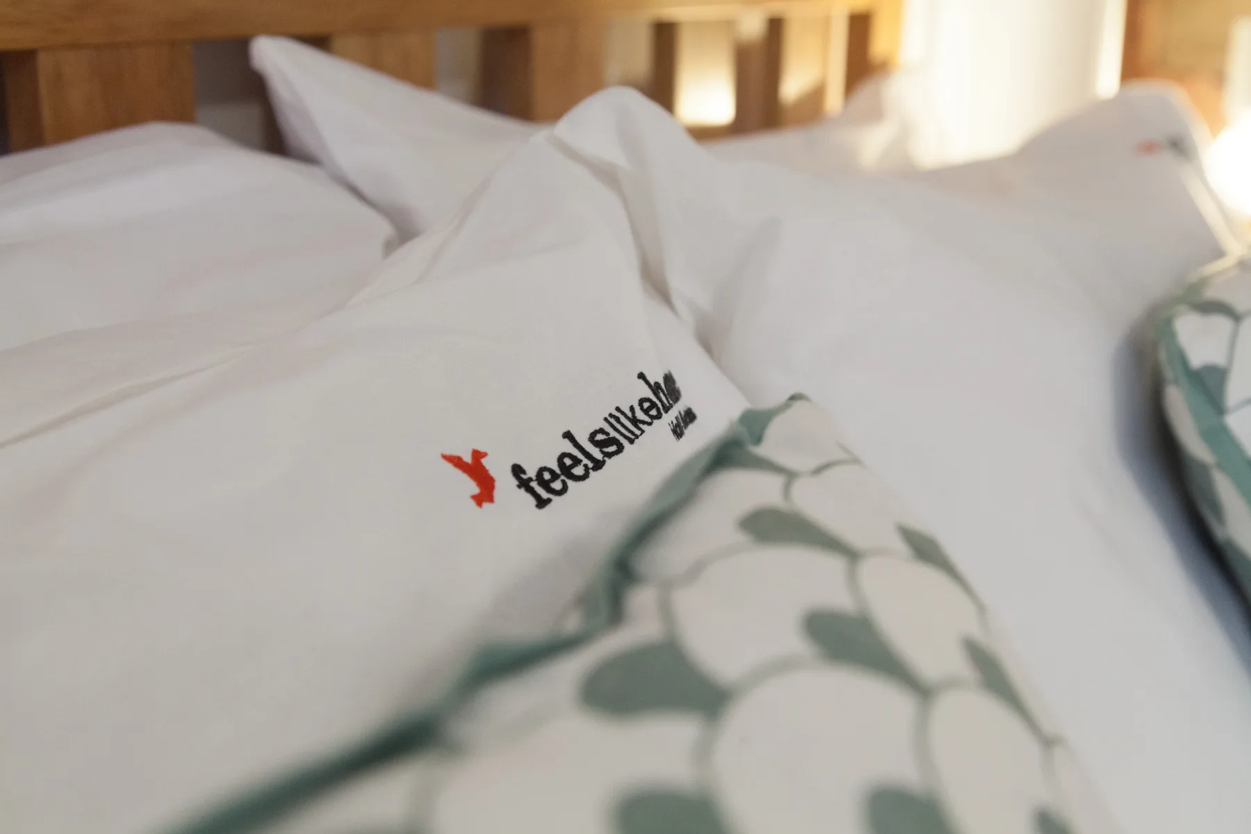 Una cama con ropa de cama blanca y una manta estampada.