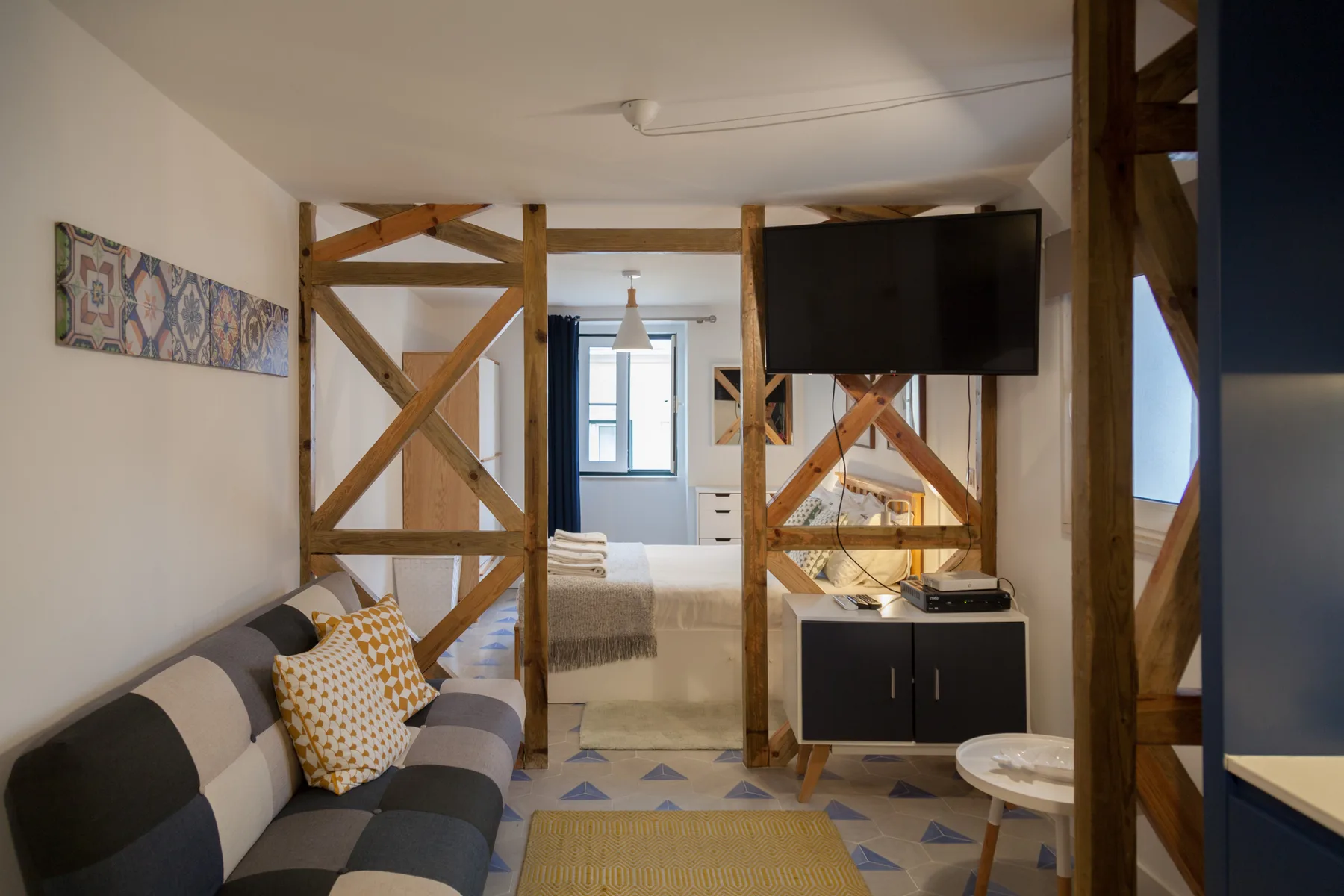 Estudio con una cama, asientos y un televisor.