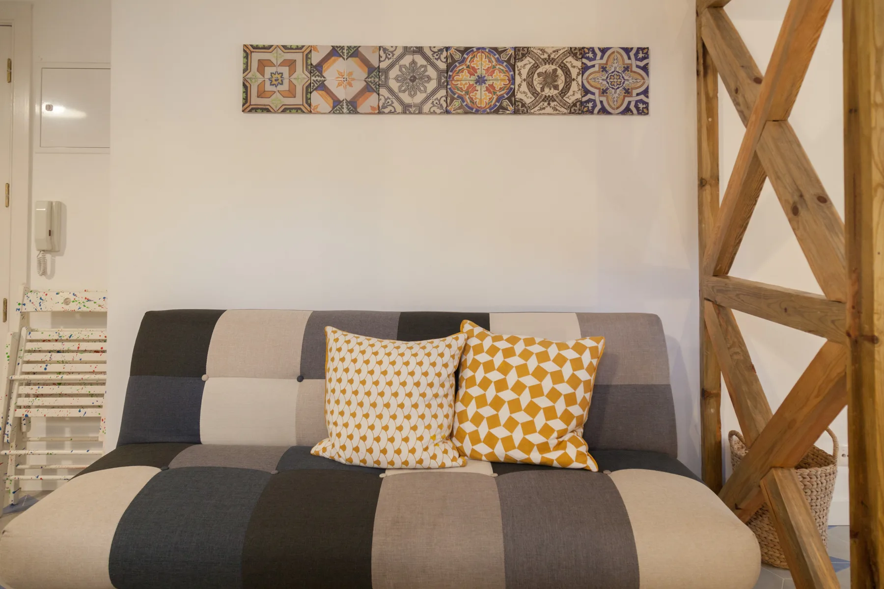 Una pequeña zona de estar con un sofá estampado y azulejos decorativos en la pared.