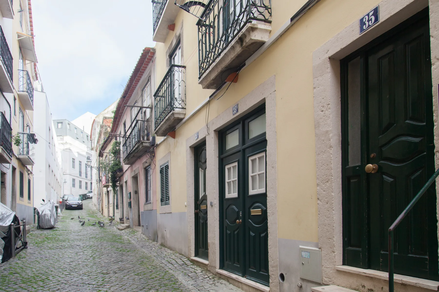 Una calle estrecha empedrada, flanqueada por edificios coloridos con balcones.