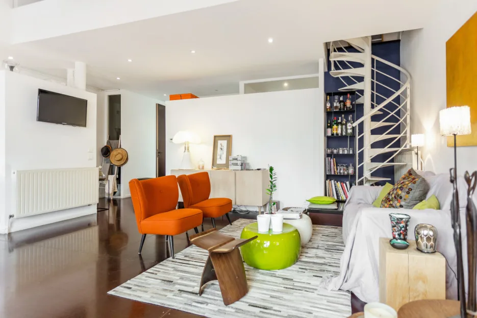 Living room with orange seating, a white sofa, and a spiral staircase.