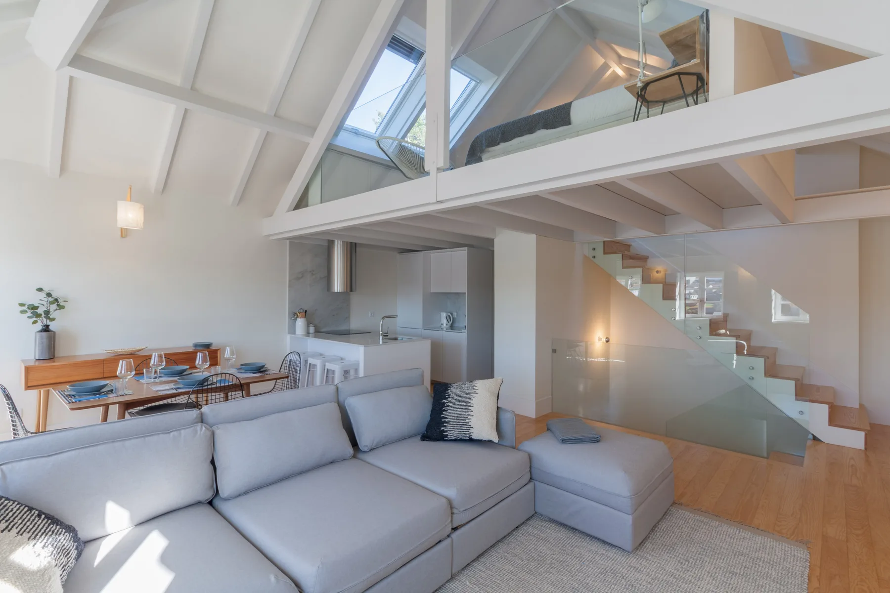 A bright living area with seating, a dining table, and a staircase.