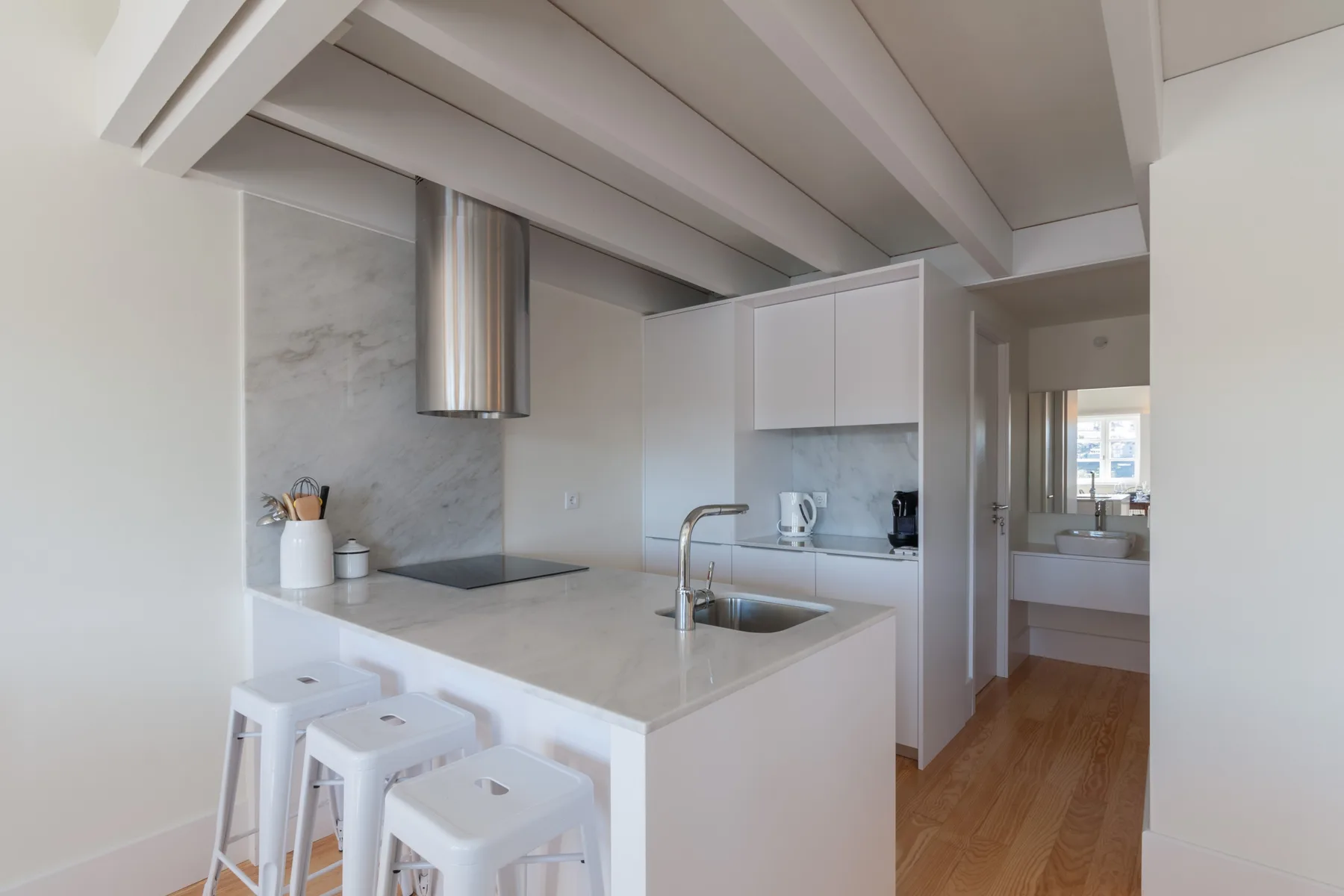 A bright apartment kitchen with a white island and stools.