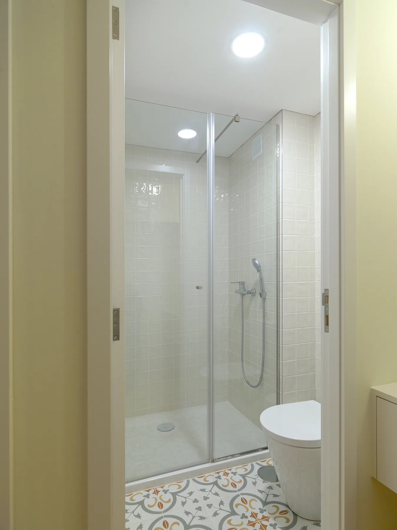 A tiled bathroom with a glass shower and toilet.