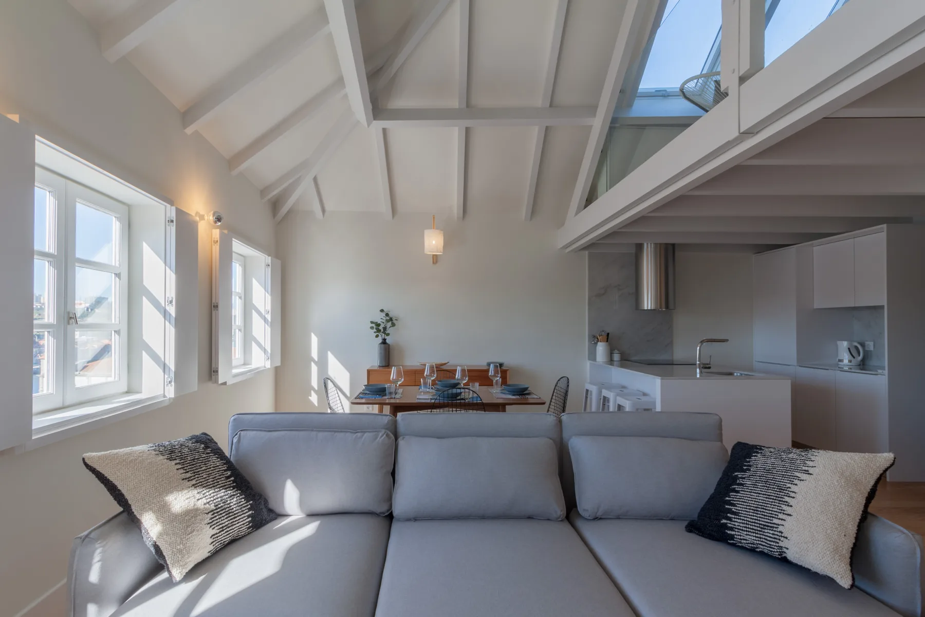 A bright living and dining area with a sofa, table, and kitchen.