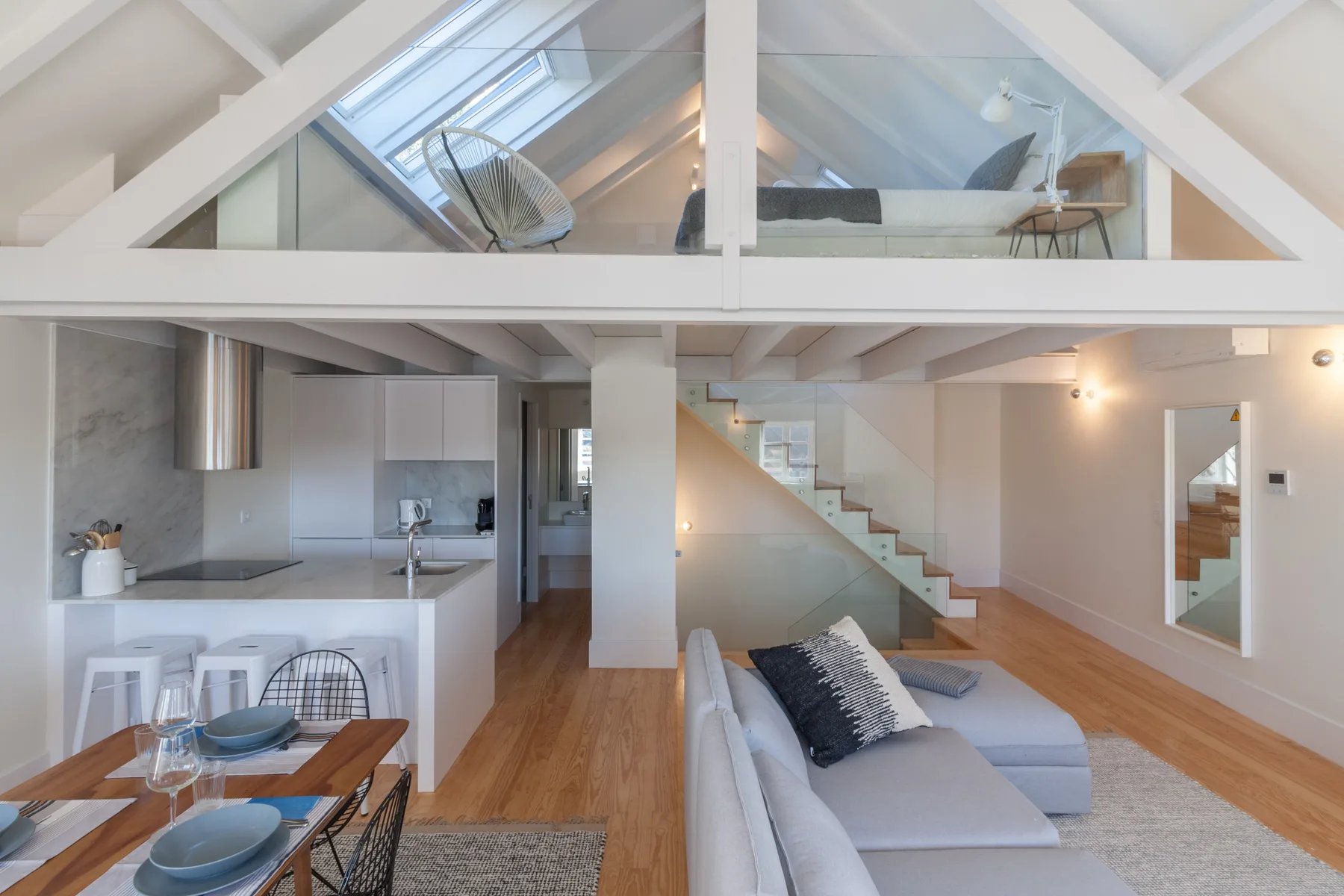 An open-plan living room and kitchen sit beneath a bright loft sleeping area.