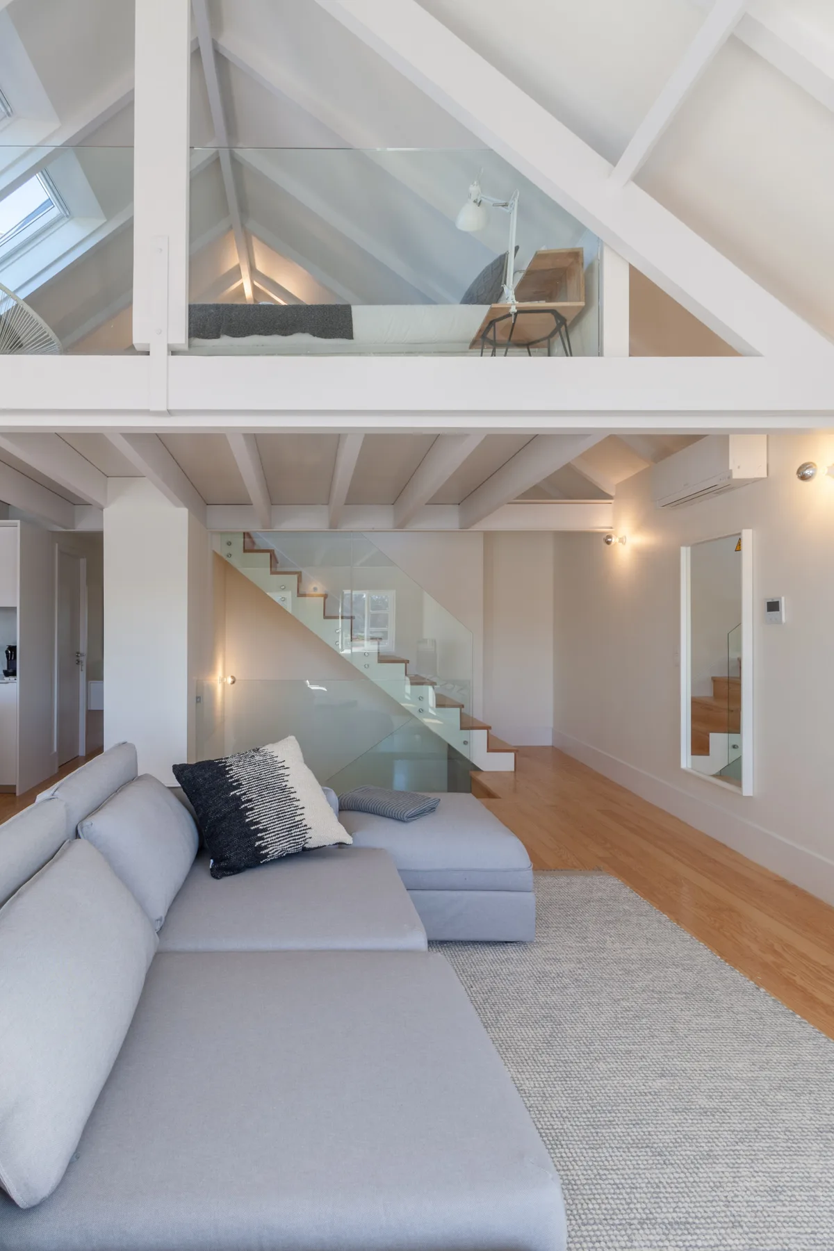 A loft living room with a sectional seating area and a staircase.