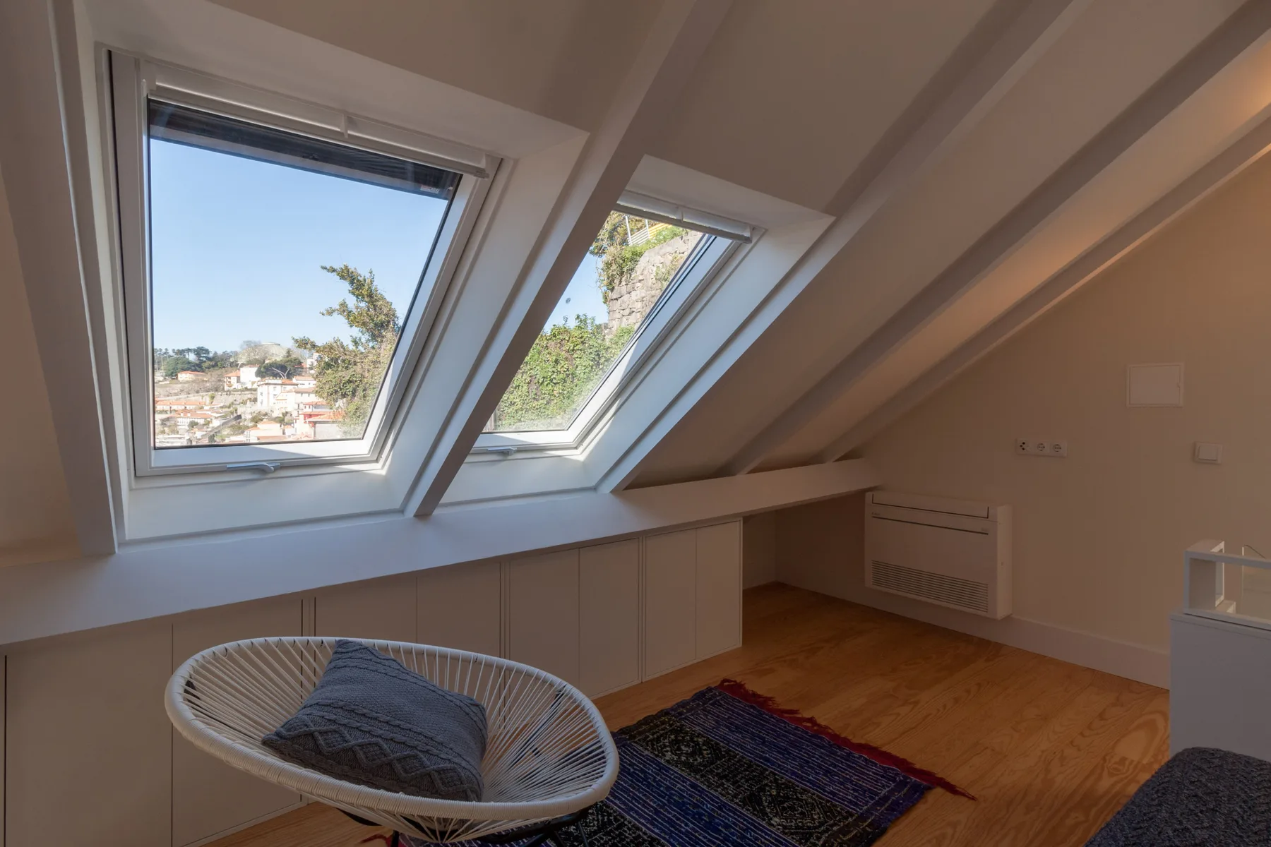 A bright attic room with sloped ceilings, skylights, and a seating area.